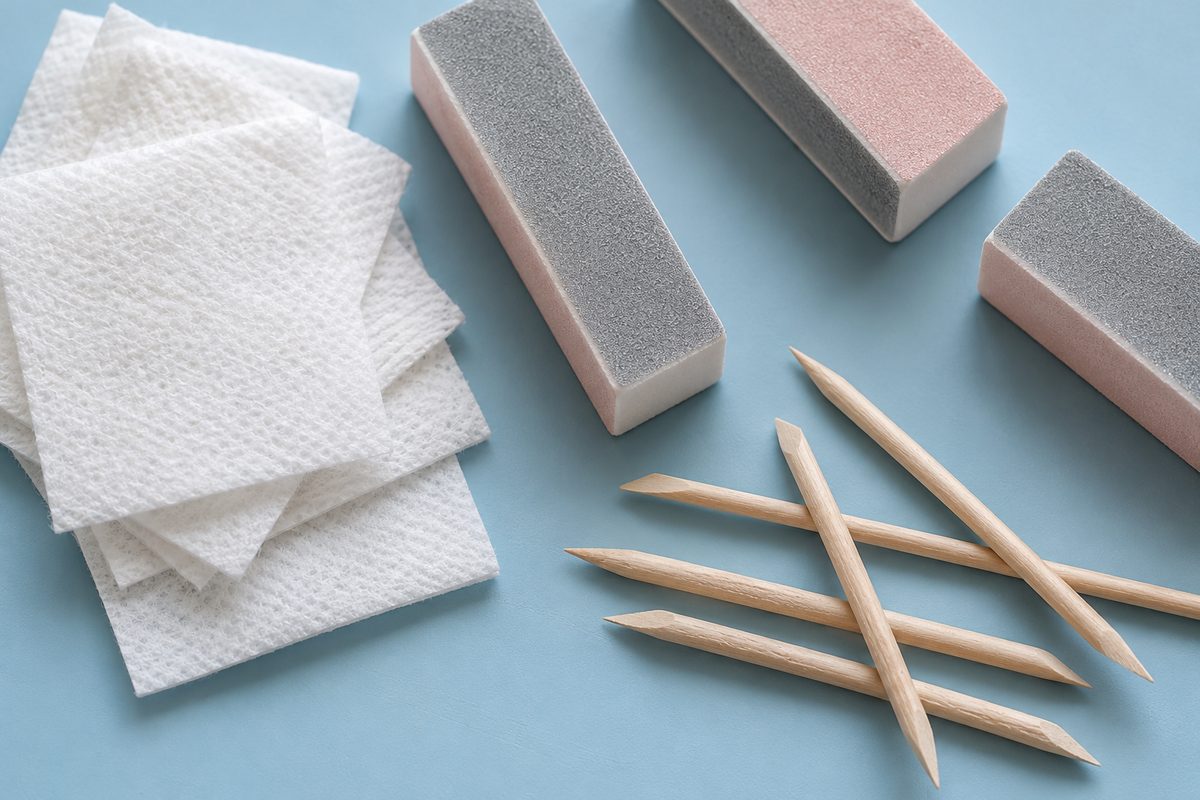 Manicure prep essentials including non-woven wipes, buffers, and cuticle sticks arranged on workstation.
